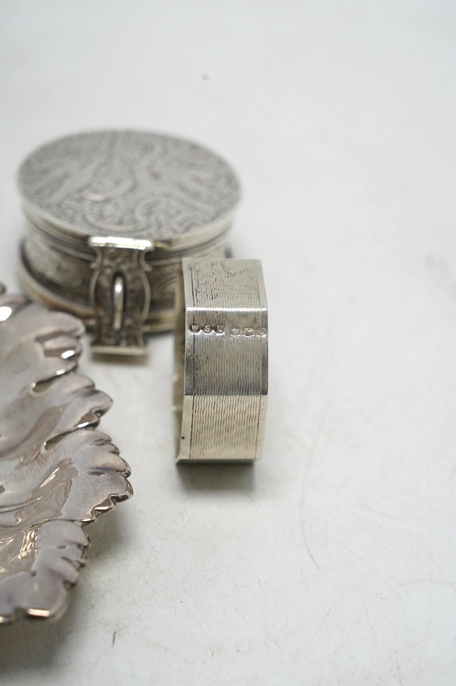 A Victorian silver circular case and cover, containing a collapsible beaker (now detached from the base), by Thomas Johnson I, London, 1873, diameter 53mm, together with a silver napkin ring and modern silver leaf dish.